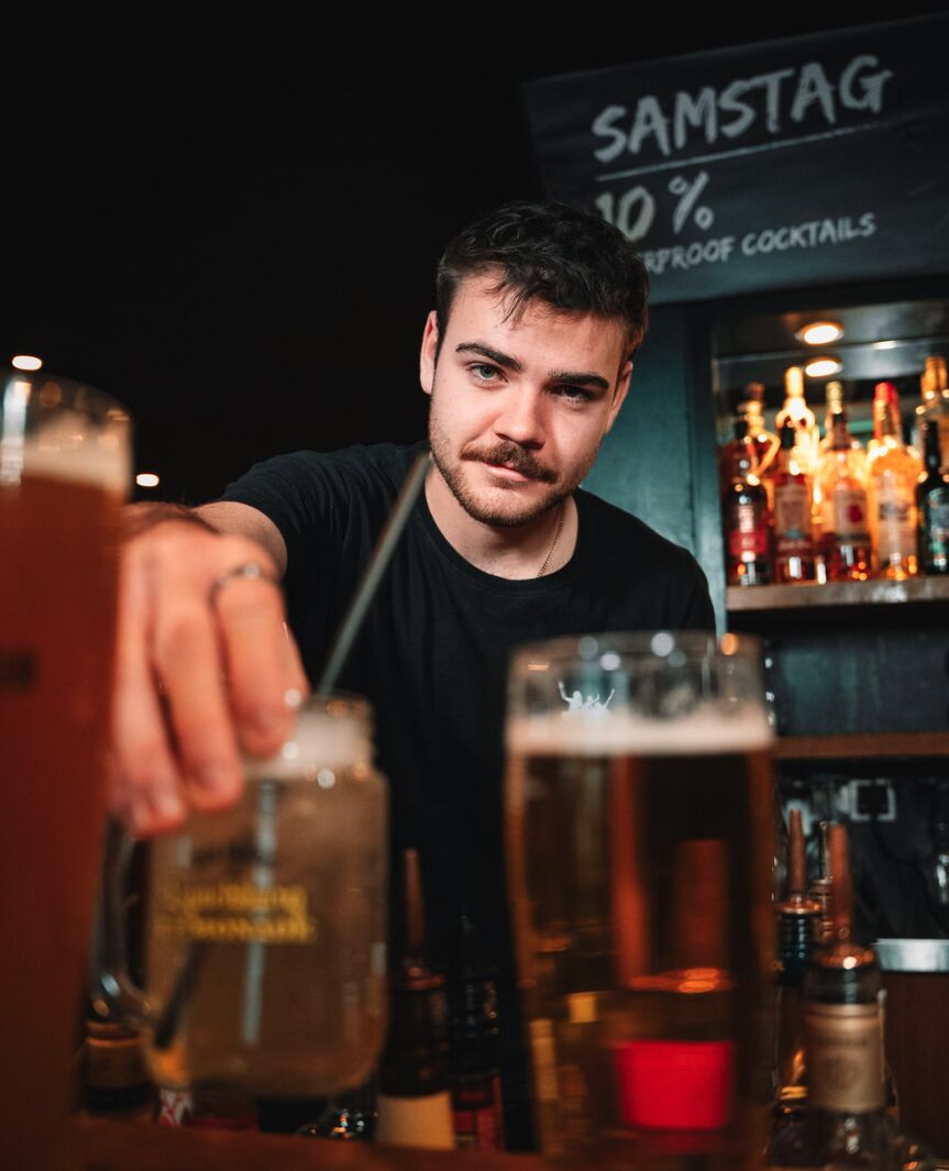 Barkeeper stellt frisch gezapftes Bier auf den Tresen